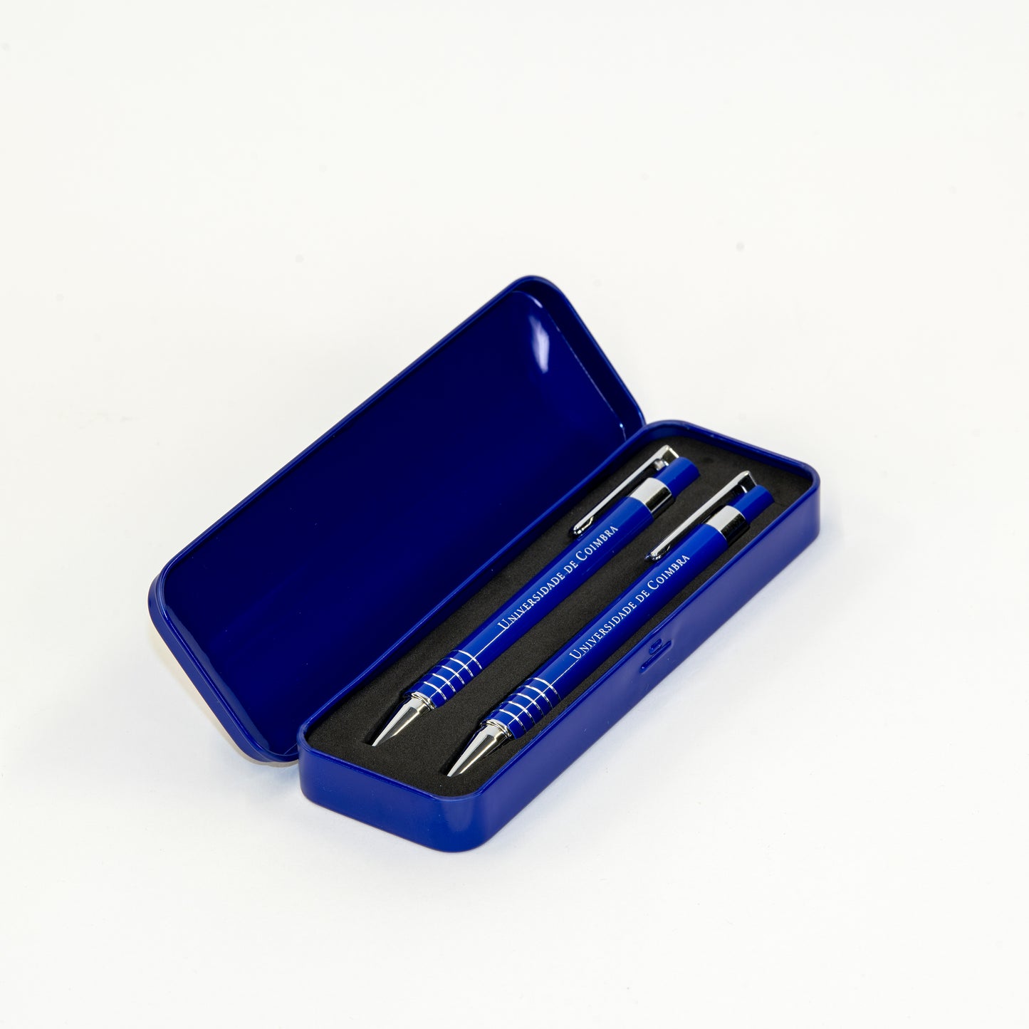 Conjunto azul de estojo de metal com esferográfica e lapiseira com a insígnia da Universidade de Coimbra.