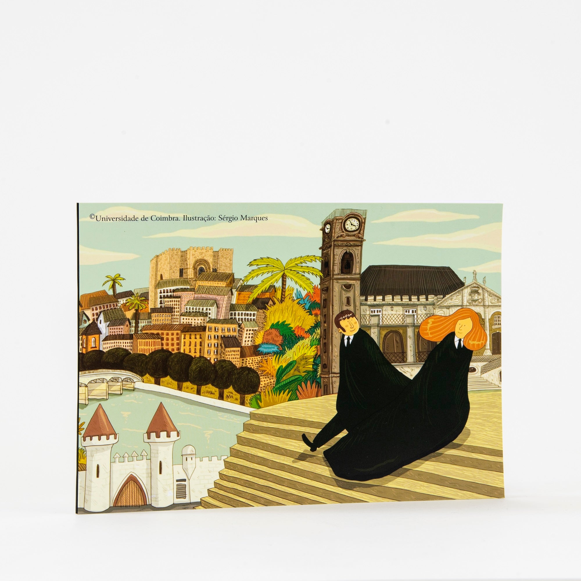 Caderno A5 de capa mole com elástico, destacando uma ilustração de Sérgio Marques com dois estudantes vestidos com traje académico da Universidade de Coimbra, próximos a pontos emblemáticos como o Paço Real, a Torre, o Jardim Botânico, a Sé Velha e o Portugal dos Pequenitos.